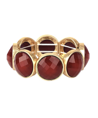 A gold-tone stretch band bracelet featuring large, faceted oval dark red gemstones, shown against a plain white background.