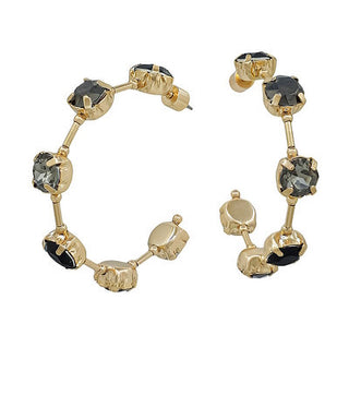Gold bracelet and earrings with black and clear gemstones on a white background