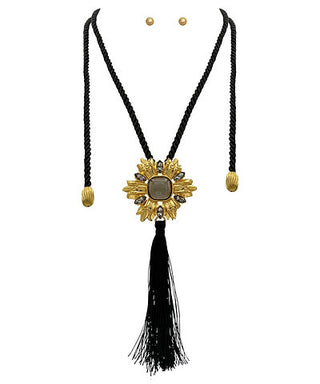 Gold necklace with black tassel on a white background