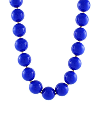 A beaded necklace made of glossy, polished cobalt blue beads separated by small gold spacers, shown against a plain white background.