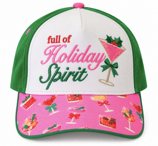 A festive baseball cap with a white front panel, green side panels and brim trim, and a bright pink brim covered in holiday cocktail prints. The front features embroidered text reading 'full of Holiday Spirit' alongside a martini glass illustration.
