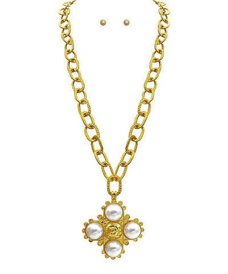 Gold necklace with a floral pendant featuring pearls on a white background