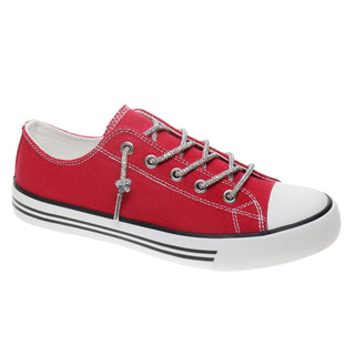 A red canvas low-top sneaker with silver glittery laces, a silver decorative charm, a white rubber toe cap, and a white sole with black stripes.