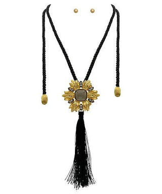 Gold necklace with black tassel on a white background